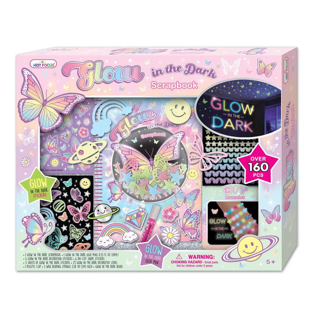 Packaging for Glow in the Dark Scrapbook kit, featuring a pink box with illustrations of butterflies, planets, and stars, and a sneak peek window displaying the glow-in-the-dark components.