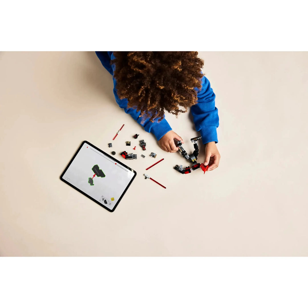 Child playing with building blocks on a beige surface with a tablet displaying a similar activity.