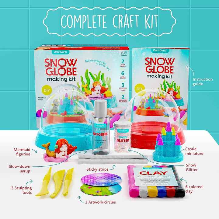 Snow globe making kit with components and packaging on a white surface against a blue tiled wall.