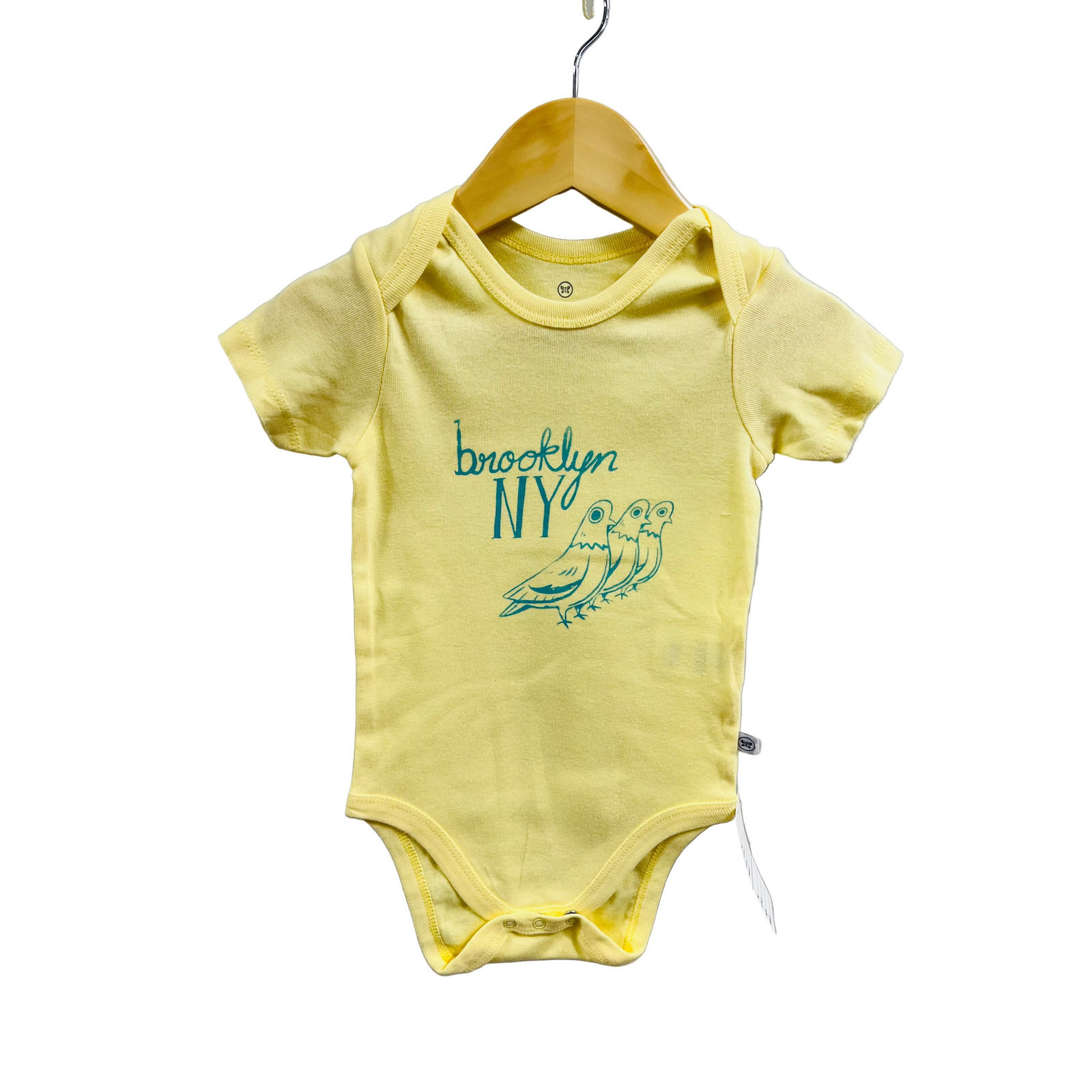 Yellow baby onesie with 'Brooklyn NY' and bird design on a hanger against a white background