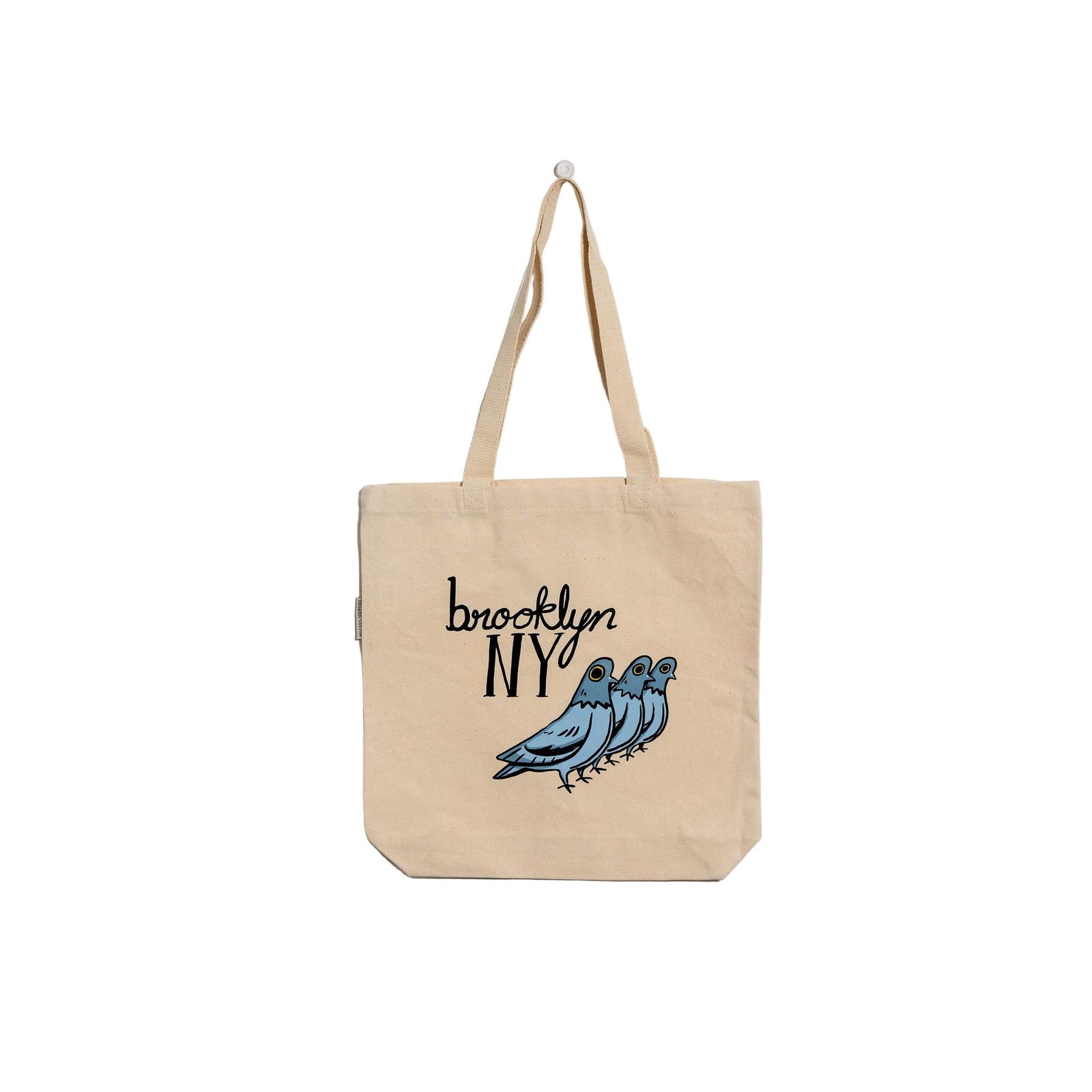 Beige tote bag with 'Brooklyn NY' and bird design on a textured white background