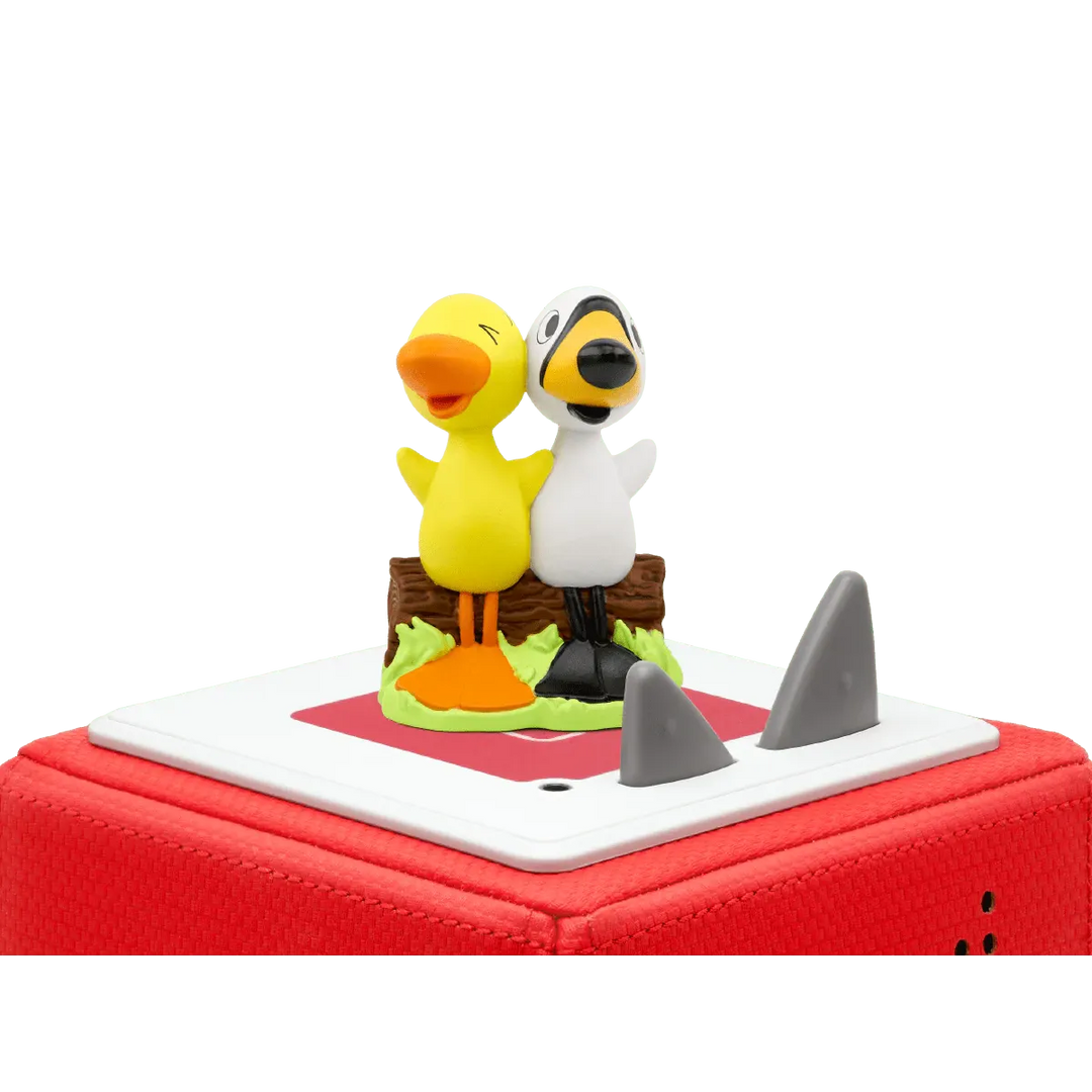 Two cartoon duck figurines on a red toy boat with shark fin.