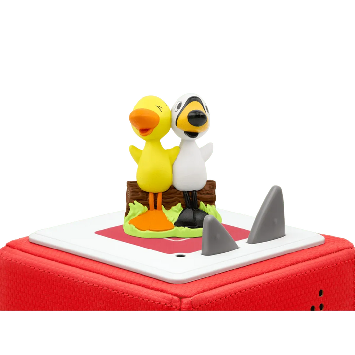 Two cartoon duck figurines on a red toy boat with shark fin.