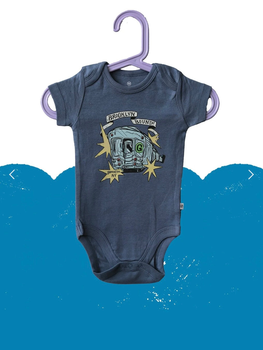 Navy blue baby onesie with graphic design on a hanger against a blue background