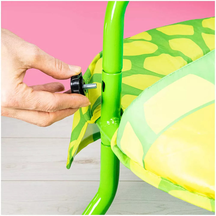 Hand adjusting a screw on a green and yellow chair with a pink background