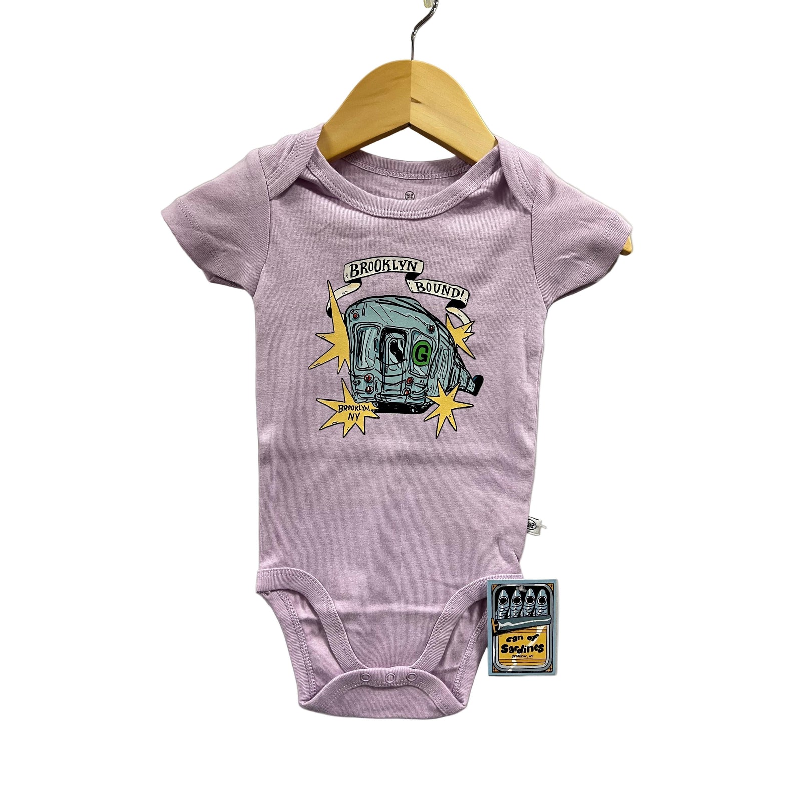 Purple baby onesie with graphic design on a hanger against a gray background