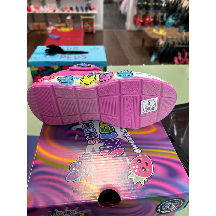 Pink shoe-shaped container with colorful designs on a colorful surface