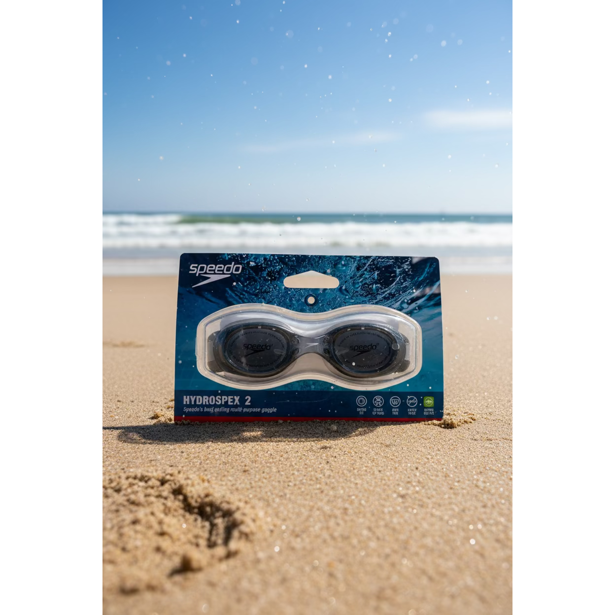 Speedo HydroDropeX 2 swim goggles in their original retail packaging, displayed on a countertop with a red tumbler and a VISA card in the background.