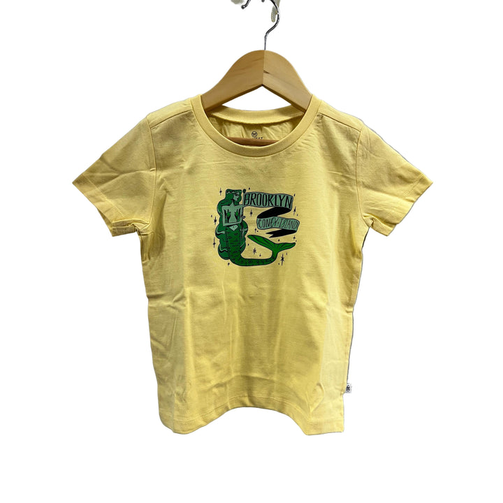 Yellow t-shirt with green graphic design on a hanger against a gray background