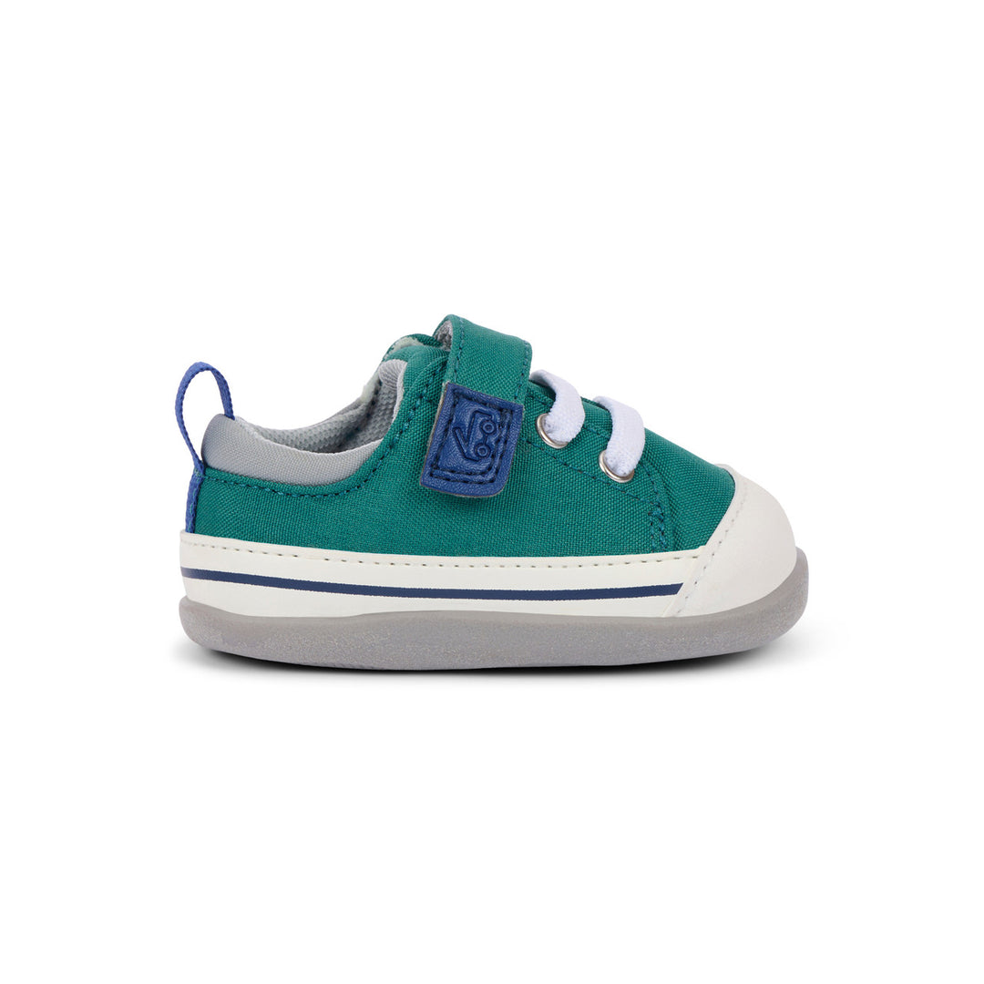 Green children's sneaker with a strap on a white background