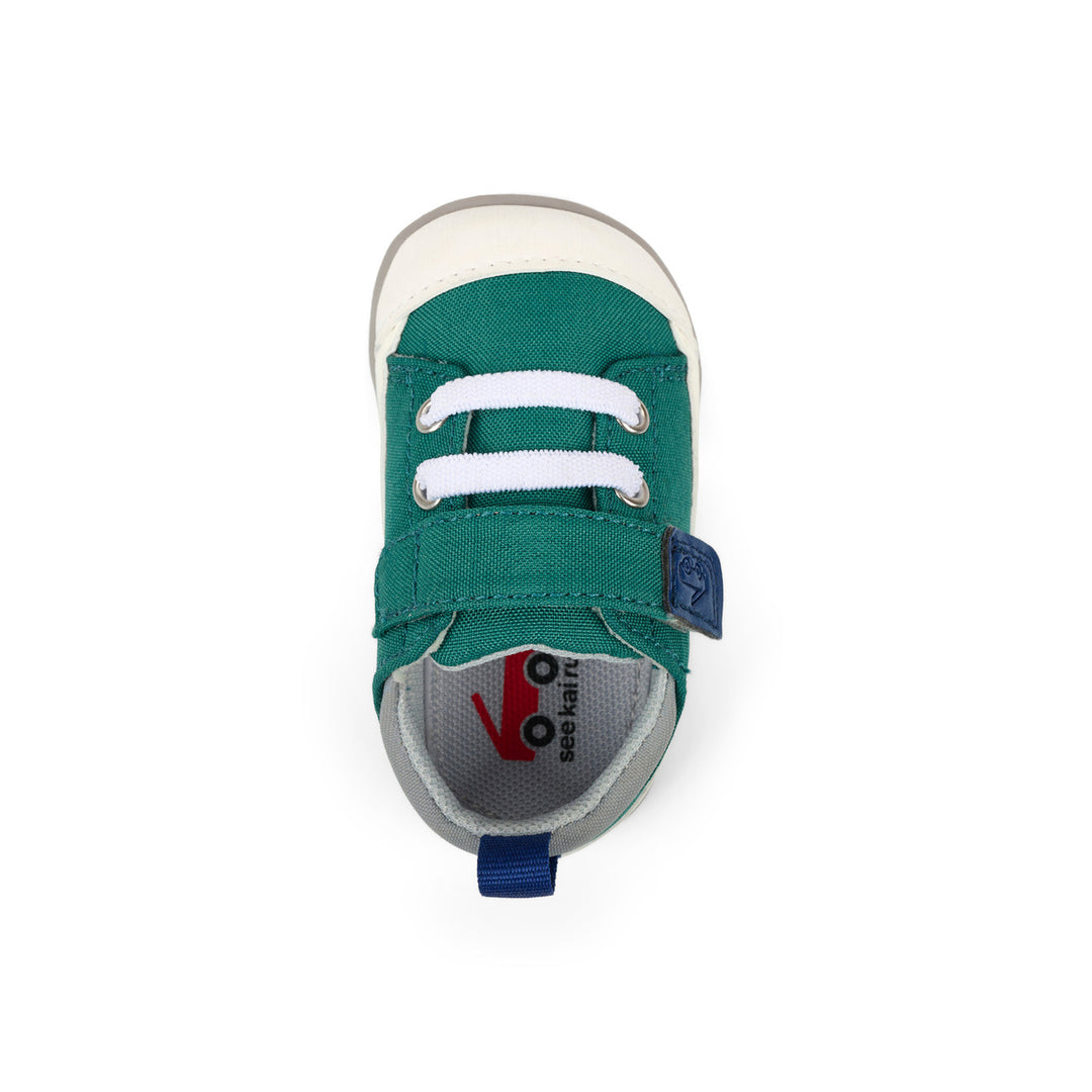 Green children's sneaker with white laces on a white background