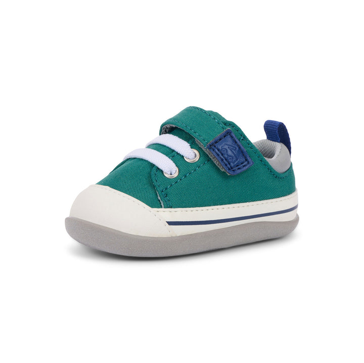 Green children's shoe with a white sole on a white background