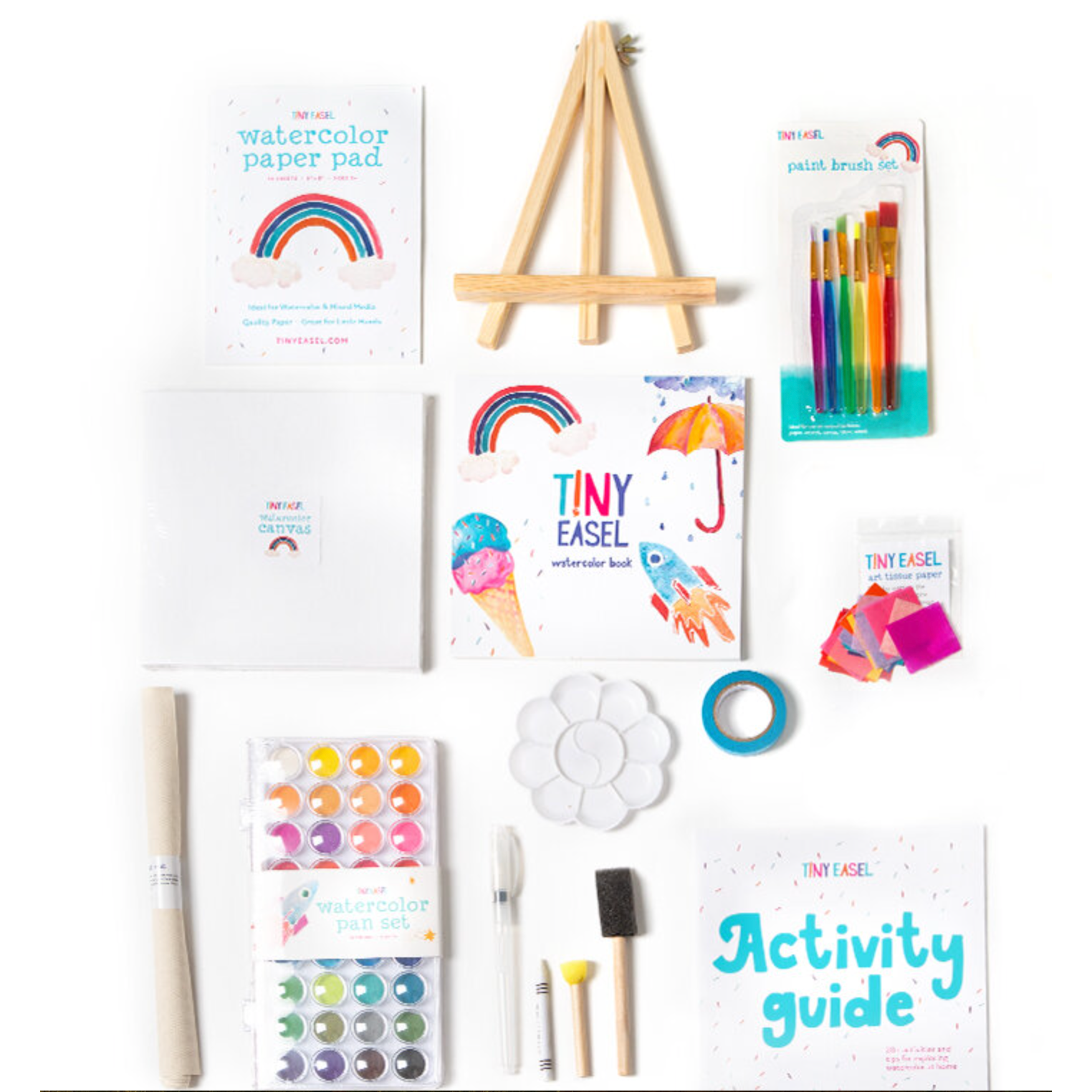 An array of art supplies including watercolor paints, brushes, pencils, paper, and an easel arranged on a white background.