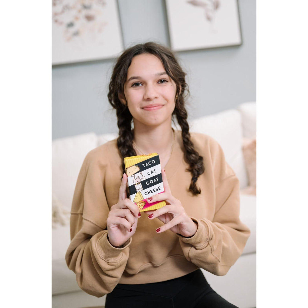 Person holding a colorful box with text, sitting on a couch.