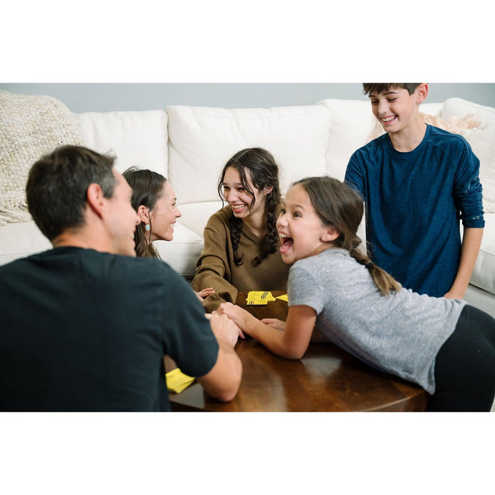 Family of five gathered around a table, likely playing a game together.