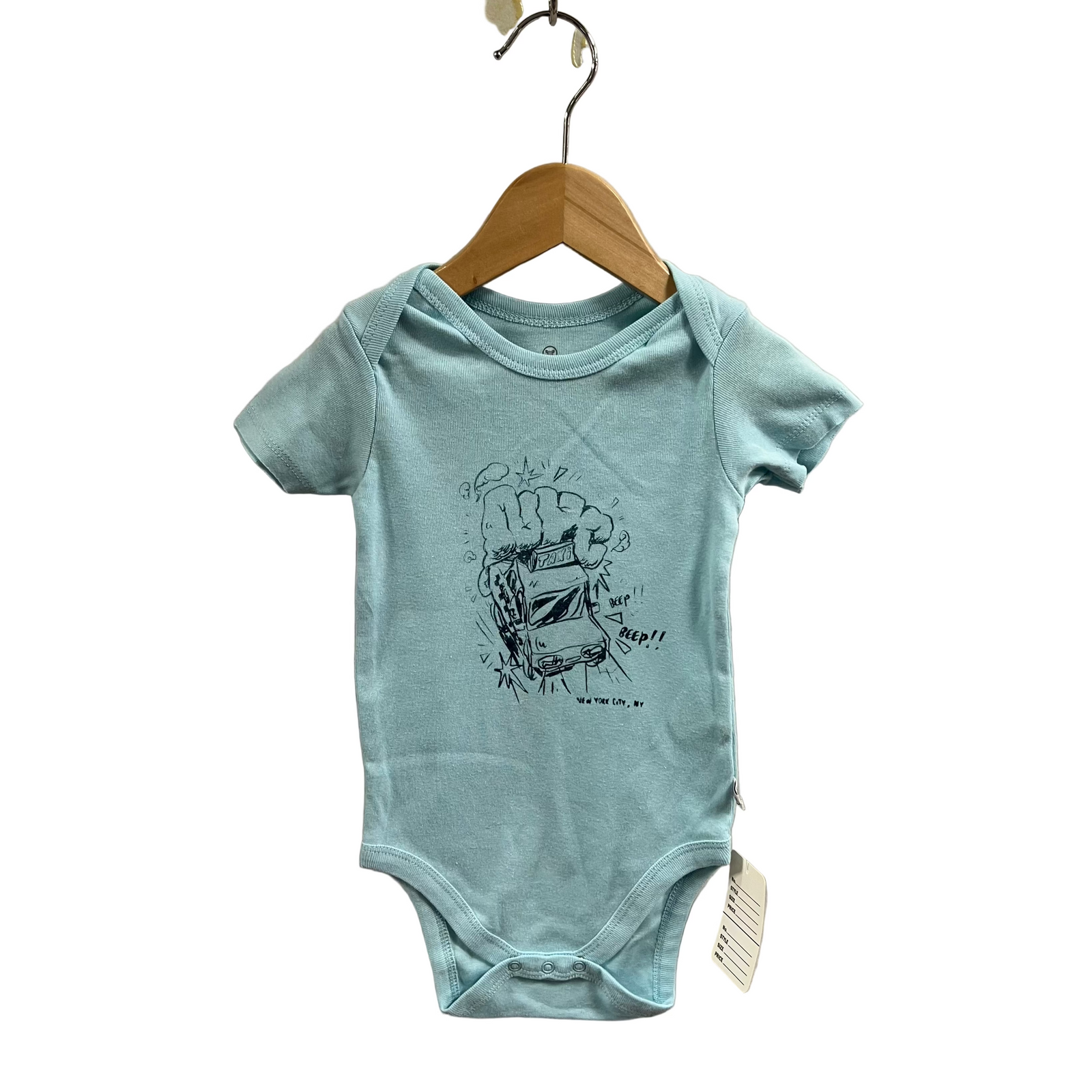 Light blue baby onesie with a graphic design on a wooden hanger against a beige wall.