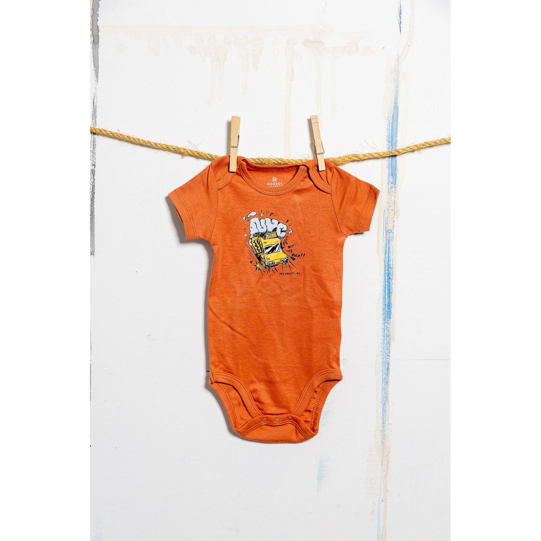 Orange baby onesie with a graphic design hanging on a clothesline.
