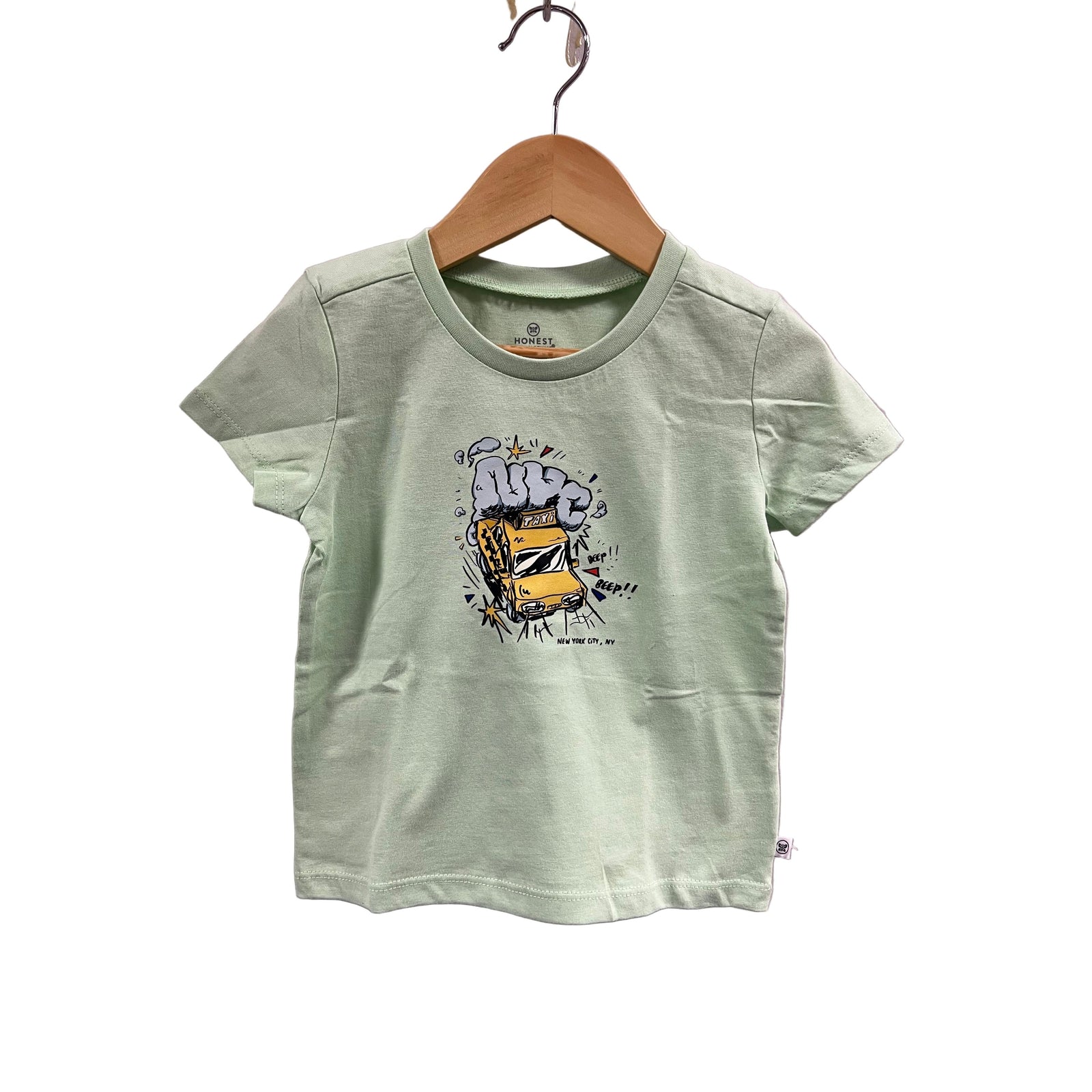 Light green t-shirt with a graphic design on a wooden hanger against a light purple wall.