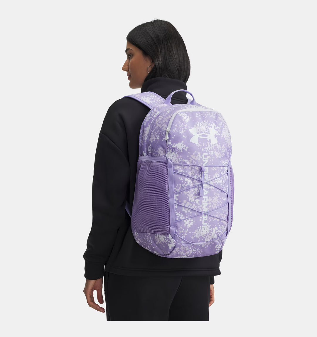 Person wearing a purple backpack with floral pattern on a white background