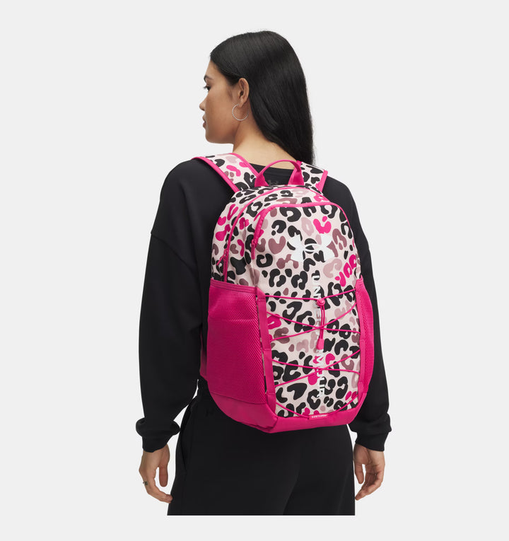 Person wearing a pink backpack with leopard print design on a white background