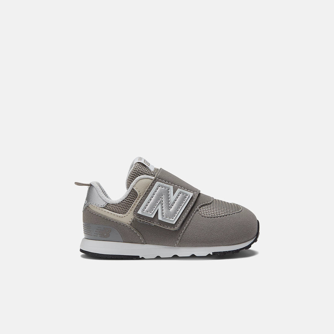 A toddler-sized New Balance 574 sneaker with hook and loop closure, in a gray color.