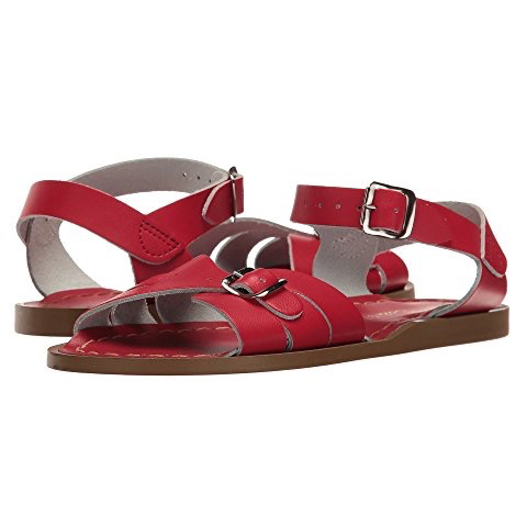 A red sandal with buckle closures and a flat rubber outsole, designed for big kids or adults.