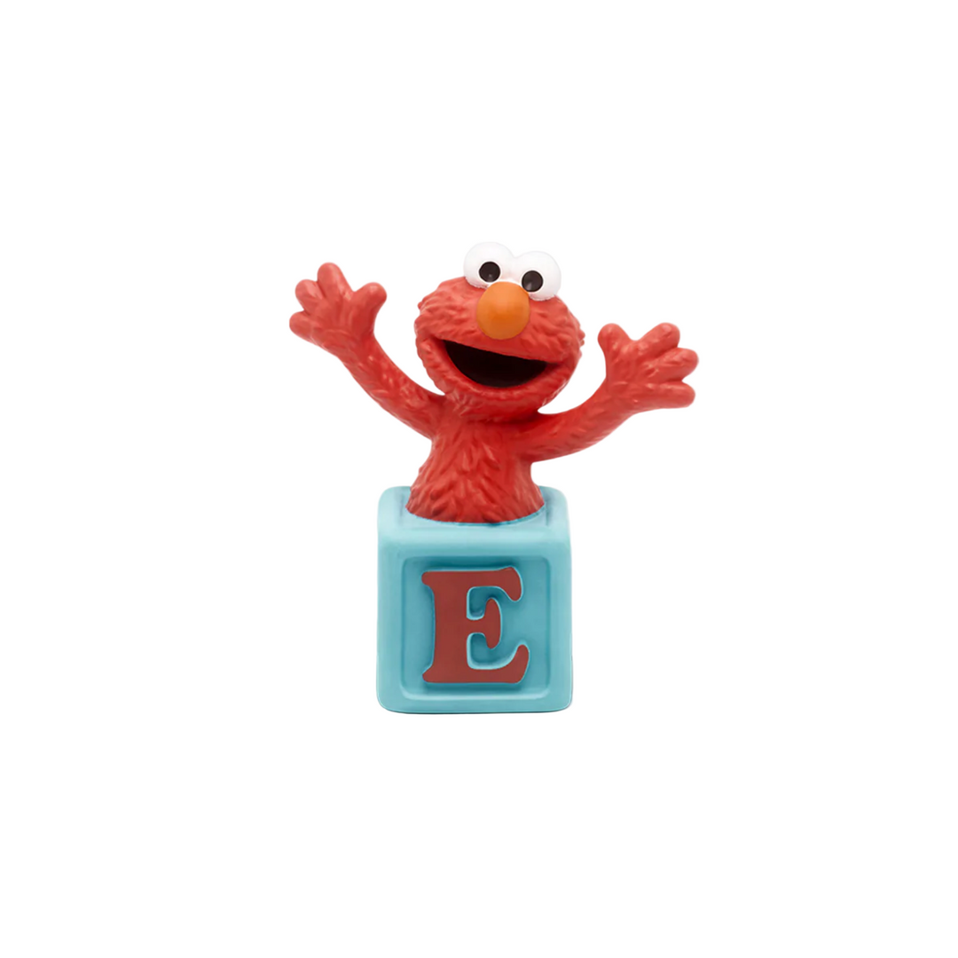A plastic figure of Elmo from Sesame Street, placed on a blue square base with the letter 'E' on it.